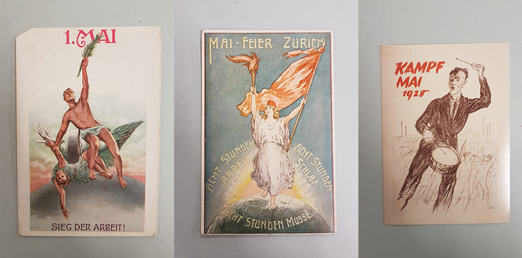 Auf dem Bild zu sehen sind drei Postkarten anlässlich des 1. Mai-Feiertags. Auf einem siegt die Arbeit, verkörpert durch einen Mann, mit den Worten "Sieg der Arbeit". Auf dem zweiten winkt eine Dame mit einer roten Fahne und wirbt für "8 Stunden Arbeit, 8 Stunden Musse, 8 Stunden Schlaf". Auf der dritten Karte trommelt ein Mann neben einem Roten Schriftzug "Kampf Mai 1925".
