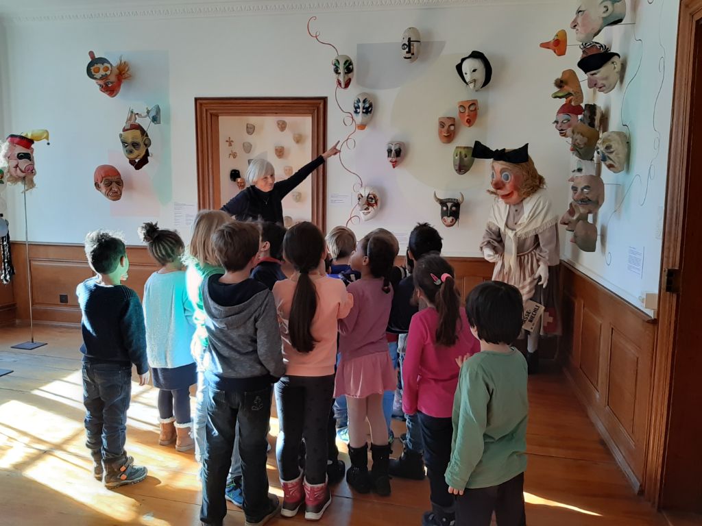 Margrit Gontha zeigt vor den Kindern auf die aufgehängten Larven in der Ausstellung.