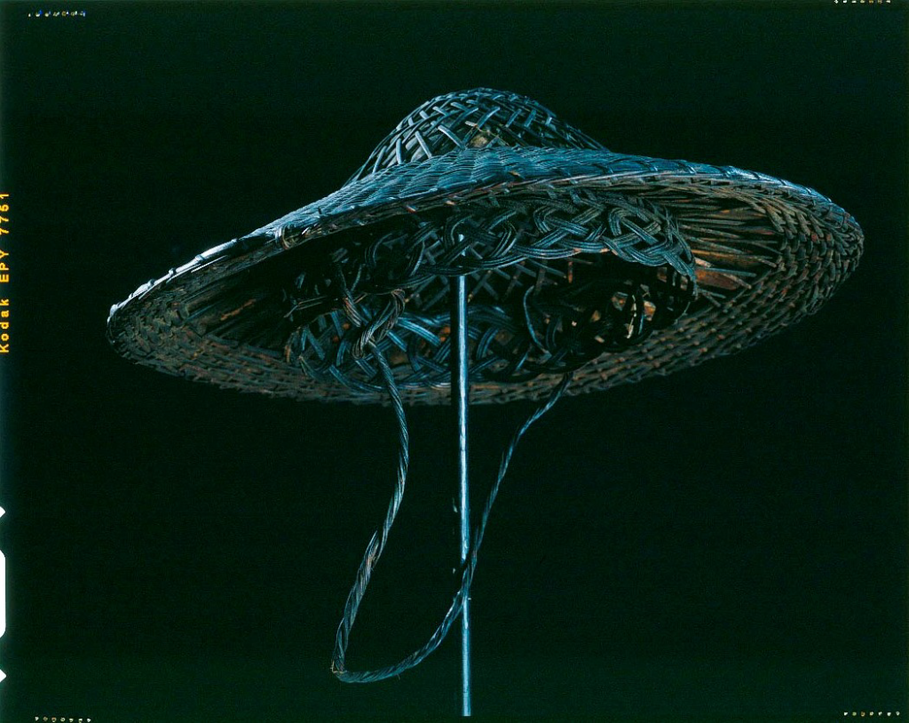 Der abgebildete Hut ist rund, gleicht einem Sonnenhut und wurde kunstvoll aus Pflanzenfasern geflochten.