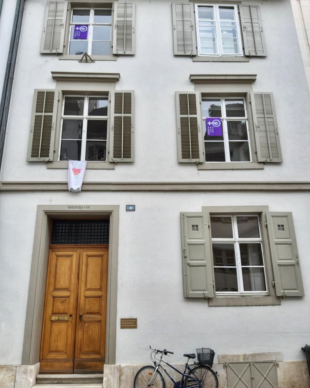 Das Foto zeigt das Museum von aussen an der Augustinergasse. In drei von fünf Fenstern hängen violette Fahnen, die auf den Frauenstreik hinweisen