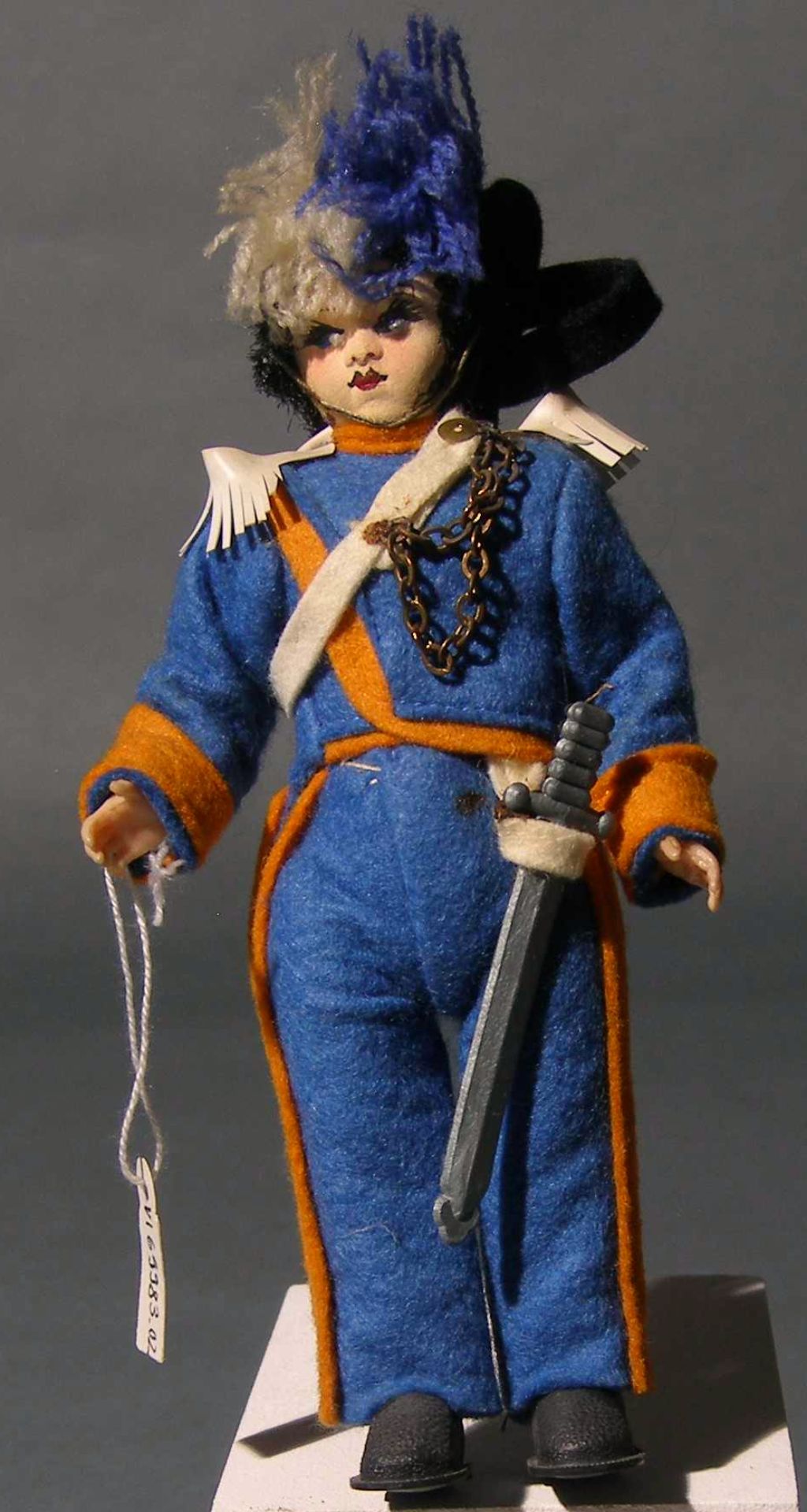 Das Foto zeigt eine Puppe, die eine Wache aus San Marino darstellt. Sie trägt ene blau-orange Uniform und einen Hut mit Fedebusch sowie ein Schwert.