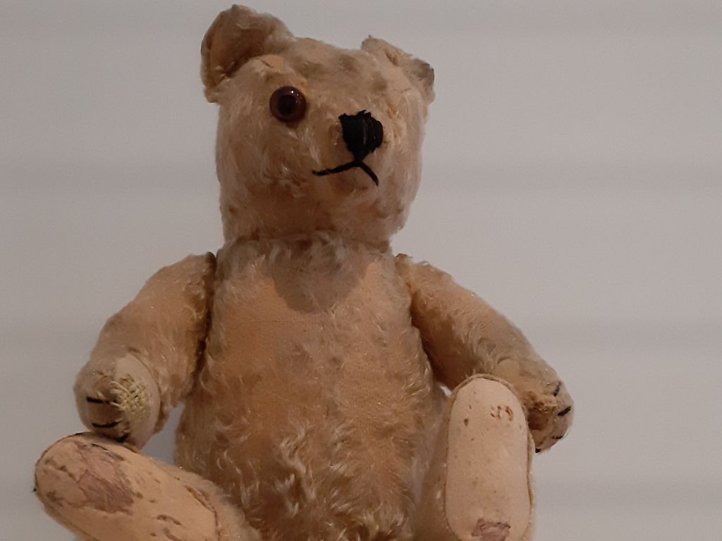 Teddybär, schon alt, mit abgewetztem Fell, nur einem Auge und am linken Fuss Stopfspuren