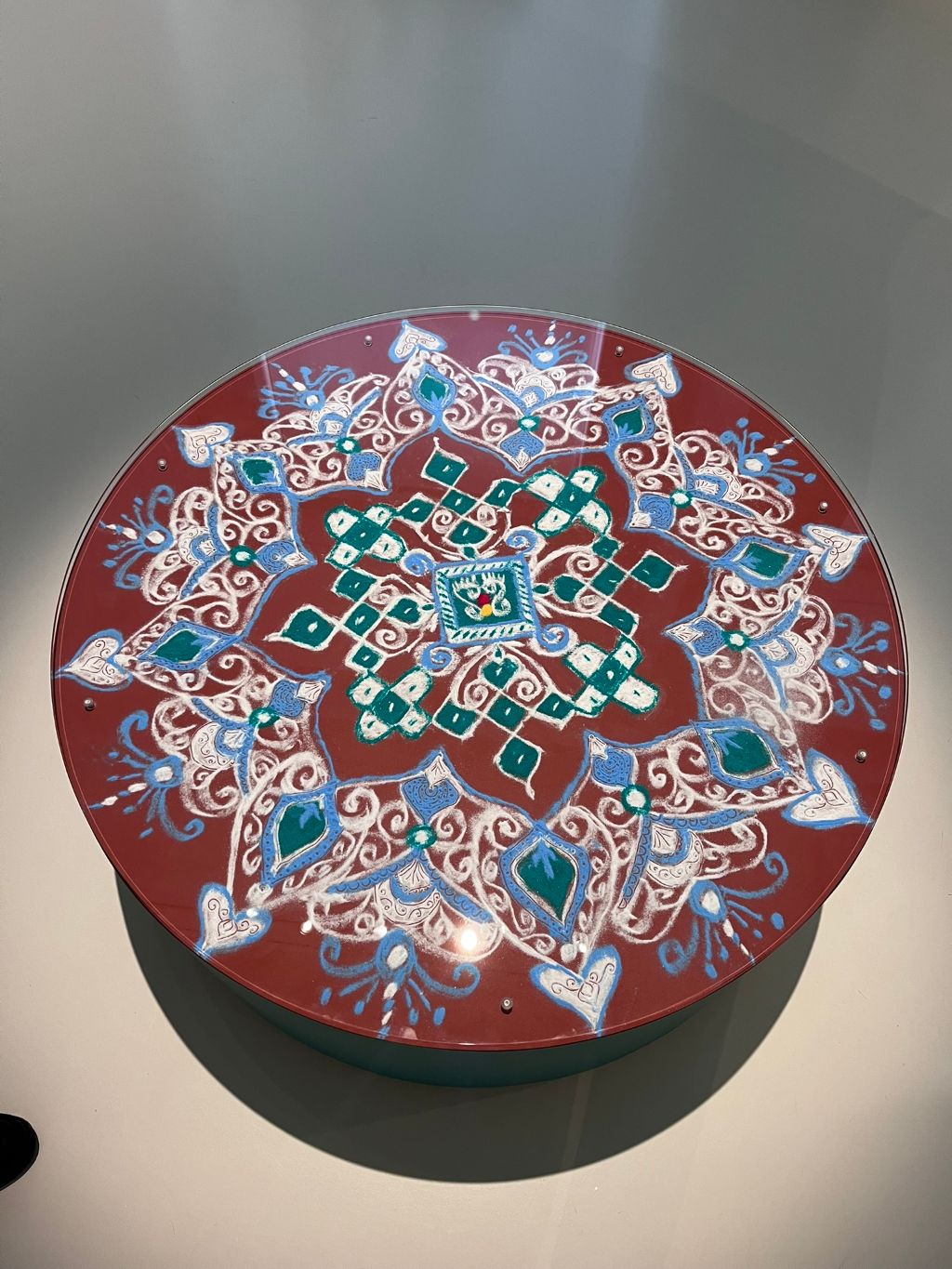 Ein rundes Tischchen, auf dessen Platte eine Blüte in verschiedenen Farben gestreut wurde.