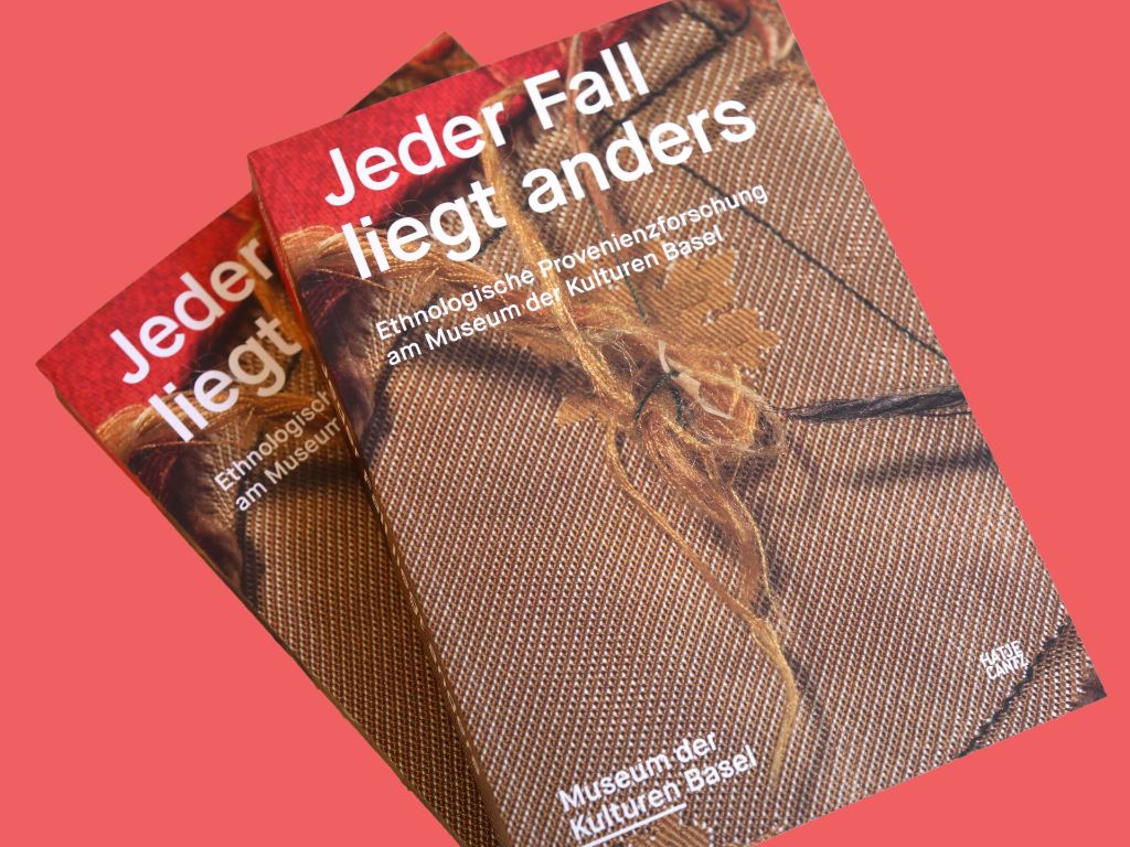 Zwei identische Bücher nebeneinander mit dem Cover oben. Der Buchtitel heisst Jeder Fall liegt anders – Ethnologische Museum der Kulturen Basel. Abgebildet ist ein Detail eines Basler Fasnachtskostüms mit bräunlich-rotem Stoff, in der Mitte zusammengehalten von langen Fäden.