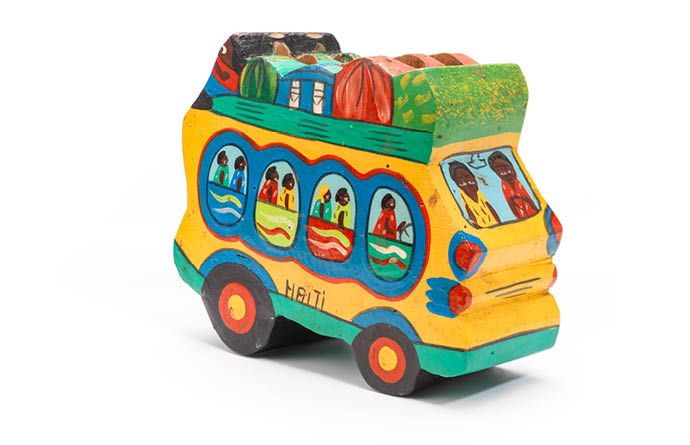 Zu sehen ist ein farbenfroher Holzbus, auf den Passagiere und Gepäck aufgemalt ist